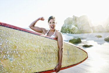 Caucasian surfer flexing muscle at beach - BLEF04035