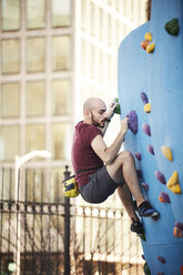 Hispanic man climbing outdoor climbing wall - BLEF04128
