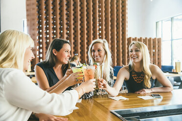 Caucasian women toasting at bar with cocktails - BLEF04146