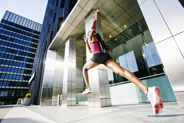 Black woman running and jumping on city sidewalk - BLEF04197