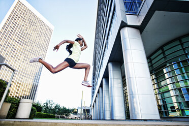Schwarze Frau läuft und springt auf dem Bürgersteig der Stadt - BLEF04199