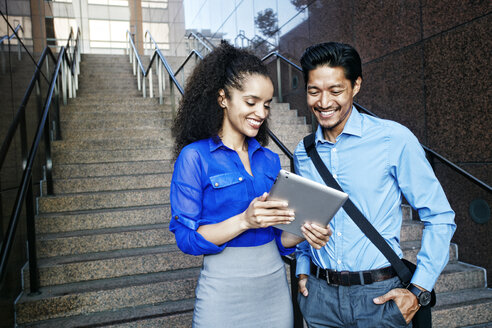 Lächelnde Geschäftsleute, die ein digitales Tablet im Freien benutzen - BLEF04220