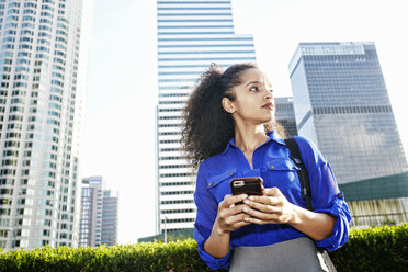 Hispanic businesswoman texting on cell phone outdoors - BLEF04226