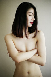 Nackte asiatische Frau mit verschränkten Armen, die die Brüste bedecken - BLEF04250