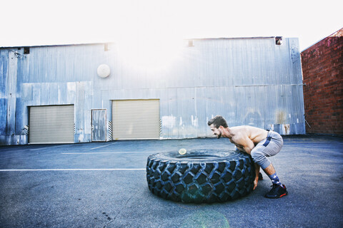 Kaukasischer Mann beim Training mit schwerem Reifen im Freien, lizenzfreies Stockfoto