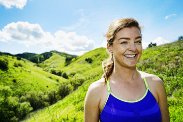 Lächelnde kaukasische Frau posiert auf einem Hügel - BLEF04287