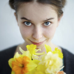 Lächelndes kaukasisches Mädchen hält gelbe Blumen - BLEF04318