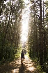 Caucasian woman walking on tree-lined forest path - BLEF04368
