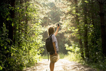 Caucasian woman photographing forest trees with cell phone - BLEF04369