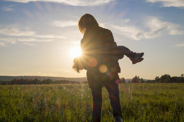 Frau mit Sohn auf einem Feld bei Sonnenuntergang - BLEF04377