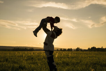 Mari Mann hebt Sohn im Feld bei Sonnenuntergang - BLEF04379