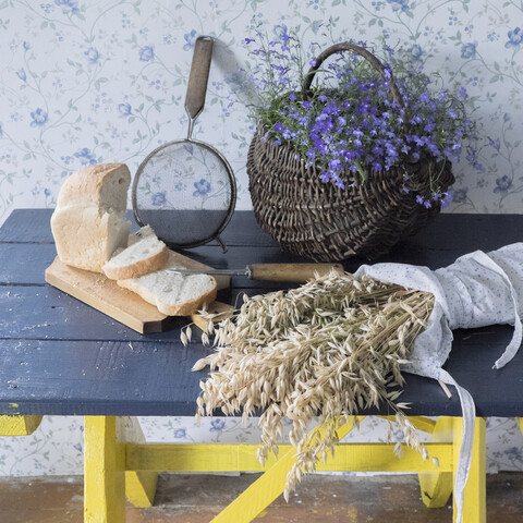 Weizen, geschnittenes Brot, Sieb und Blumen auf der Bank, lizenzfreies Stockfoto