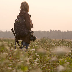 Kaukasischer Fotograf in einem Blumenfeld stehend - BLEF04388