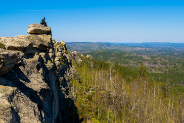 Kaukasischer Mann sitzt auf einem Bergfelsen und bewundert die malerische Aussicht - BLEF04408