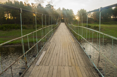 Sunbeams on wooden footbridge over river - BLEF04414