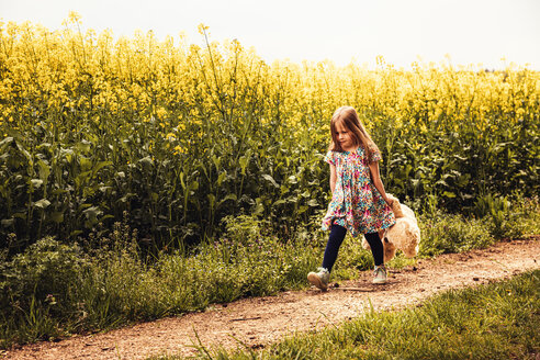 Mädchen geht allein mit Teddy und Rucksack auf einem Feldweg - SEBF00101