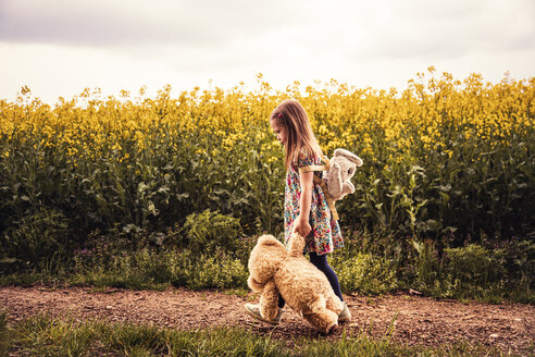 Mädchen geht allein mit Teddy und Rucksack auf einem Feldweg - SEBF00103