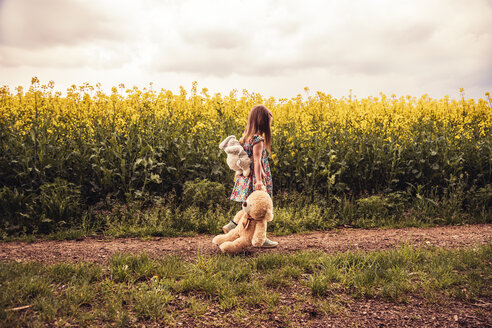 Mädchen geht allein mit Teddy und Rucksack auf einem Feldweg - SEBF00104