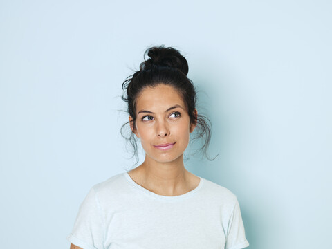 Portrait of young woman with black hair, light blue background stock photo