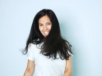 Porträt einer jungen Frau mit schwarzen Haaren, hellblauer Hintergrund - HMEF00396