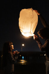Father and daughter preparing a sky lantern at night - ERRF01379