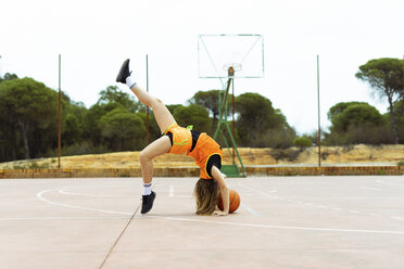 Teenage girl doing acrobatics on basketball ground - ERRF01383