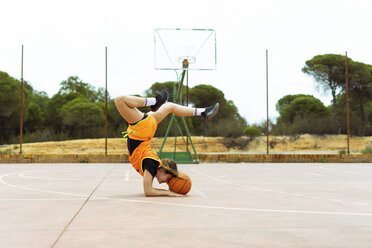 Teenage girl doing acrobatics on basketball ground - ERRF01384