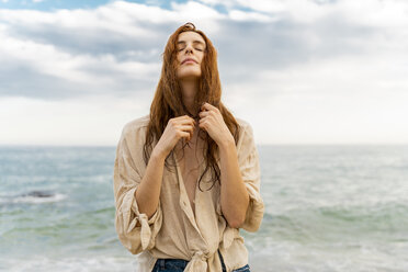 Portrait of redheaded young woman with nose piercing standing in front of the sea - AFVF02989