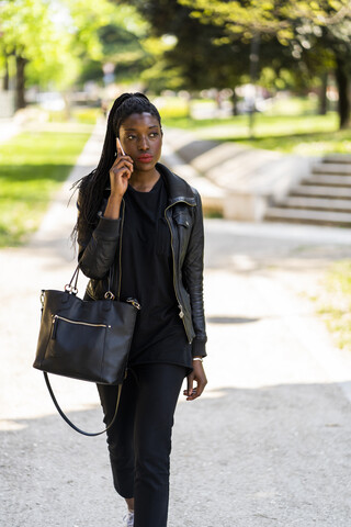 Woman on cell phone walking in urban park stock photo