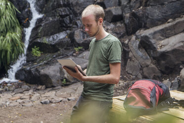 Wanderer macht eine Pause auf einem Rastplatz und benutzt ein Tablet, Barranco el Cedro, La Gomera, Kanarische Inseln, Spanien - MAMF00686