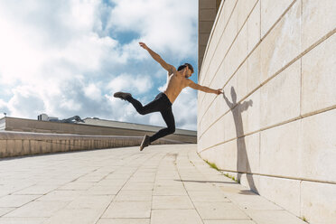 Young man doing acrobatics at a wall outdoors - AFVF03019