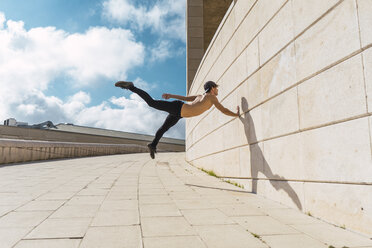 Young man doing acrobatics at a wall outdoors - AFVF03020
