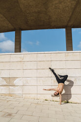 Junger Mann macht einen Handstand an einer Wand im Freien - AFVF03022