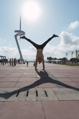 Junger Mann macht einen Handstand im Gegenlicht, lizenzfreies Stockfoto