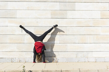 Teenager-Mädchen macht einen Handstand an einer Wand im Freien - ERRF01394