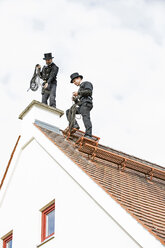 Zwei Schornsteinfeger arbeiten auf dem Dach eines Hauses - MAEF12893