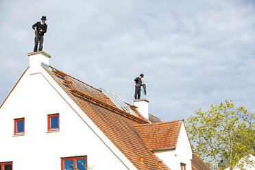 Zwei Schornsteinfeger arbeiten auf dem Dach eines Hauses - MAEF12895