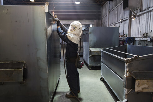 Kaukasischer Arbeiter schleift Metallbehälter in einer Fabrik - BLEF04468