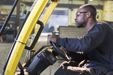 Black worker driving forklift in factory - BLEF04474