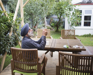 Indischer Mann fotografiert mit Handy auf der Hinterhof-Terrasse - BLEF04537