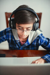Mixed Race boy listening to laptop with headphones - BLEF04542