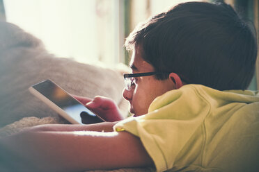 Mixed Race boy texting on cell phone near window - BLEF04545