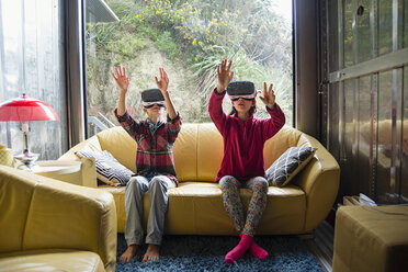 Mixed-Race-Bruder und -Schwester mit Virtual-Reality-Brille auf dem Sofa - BLEF04564