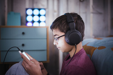 Gemischtrassiger Junge hört mit Kopfhörern auf sein Handy - BLEF04568