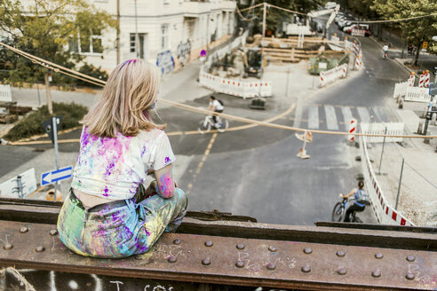 Mädchen mit Holi-Farben auf ihrer Kleidung auf einer Brücke sitzend, Deutschland - VGPF00042