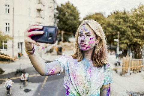 Gir Holi powder colours in her face, taking selfie, Germany stock photo