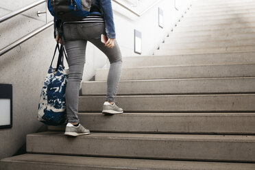 Frau mit Tasche und Rucksack beim Treppensteigen am Bahnhof - HMEF00409