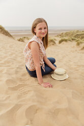 Porträt eines lächelnden Mädchens, das am Strand sitzt - NMS00306