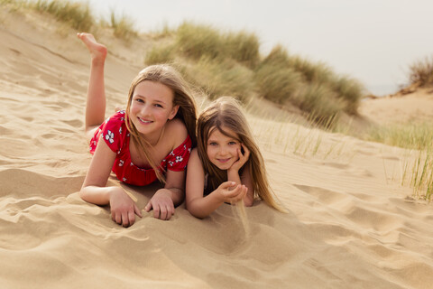 Porträt von zwei lächelnden Mädchen am Strand liegend, lizenzfreies Stockfoto