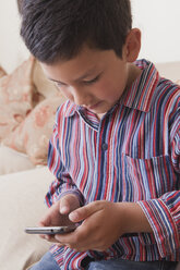 Hispanischer Junge schreibt eine SMS auf seinem Handy - BLEF04637